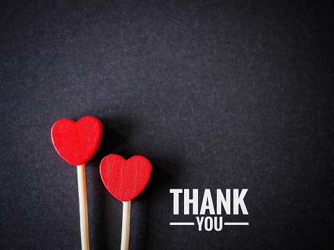 The words thank you message and two red heart on the black paper background. top view, flat lay with copy space. Greeting card.