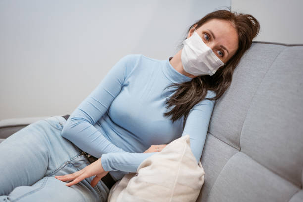 istock tired woman in protective mask on sofa with phone 1401119749