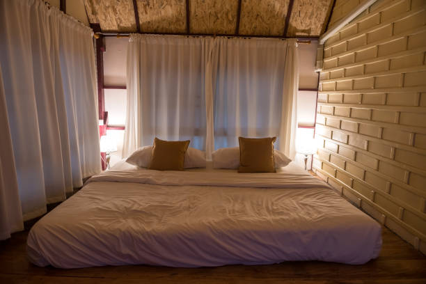 istock Big white bed in wooden bedroom at night 1401120518