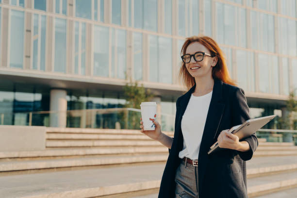 istock Successful female entrepreneur drinks takeaway coffee carries notebook and laptop 1401126324