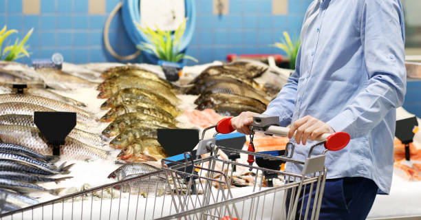 man shopping for fresh fish seafood in supermarket man shopping for fresh fish seafood in supermarket stock fish stock pictures, royalty-free photos & images