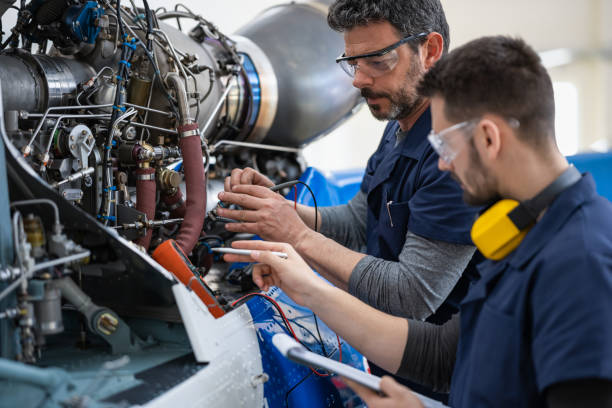 mecánicos e ingenieros de aeronaves en el hangar - industria aeroespacial fotografías e imágenes de stock