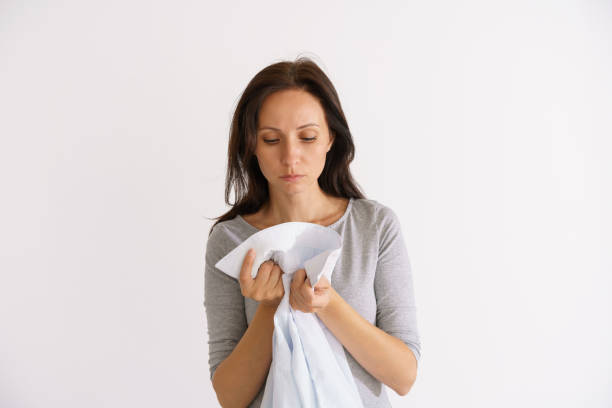 istock Woman sniffing clean shirt on light background 1401135091