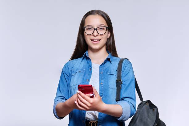 istock Teenage student with backpack smartphone looking at camera on light ackground 1401135915