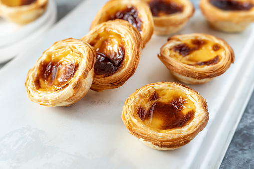 Pastel de nata freshly baked and cooling on a tray, typical Portuguese puff pastry egg custard tarts ready to eat