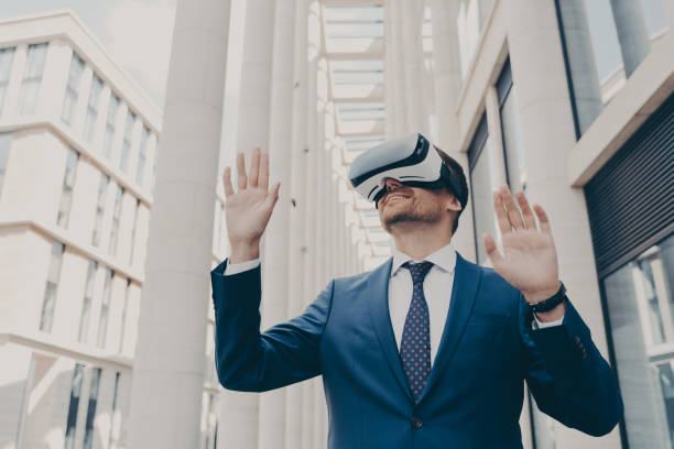 istock Young modern businessman in VR goggles on head working in augmented reality world and smiling 1401136400