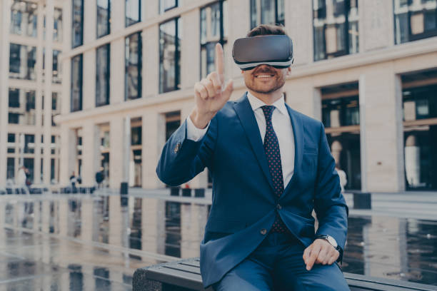 istock Young businessman in blue suit using virtual reality goggles while sitting outdoors 1401136439