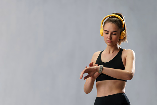 A fitness woman relaxing and listening music during her workout over grey background.