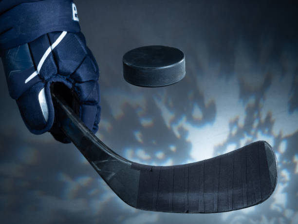 Closeup of a black ice hockey stick shooting a puck against a dreamy background. stock photo