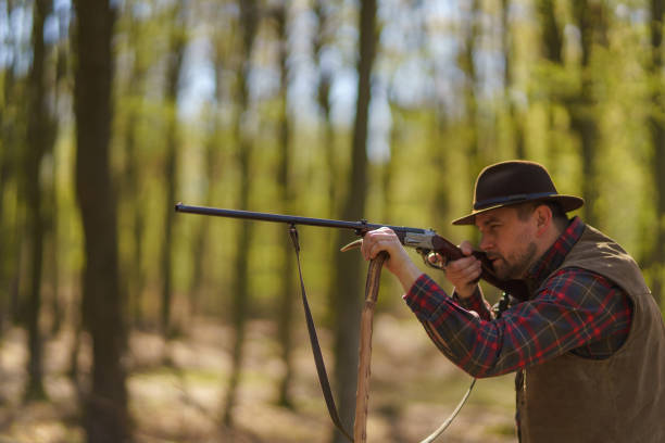istock Hunter man aiming with rifle gun on prey in forest. 1401138971