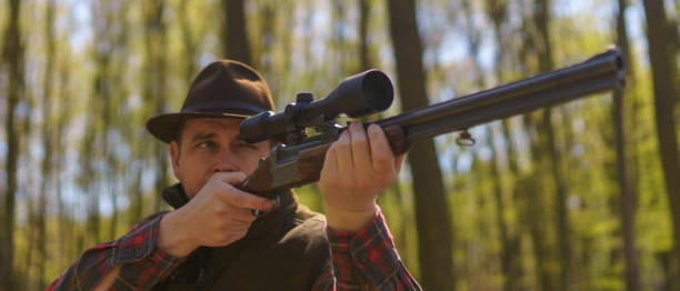 istock Hunter man aiming with rifle gun on prey in forest. 1401139067