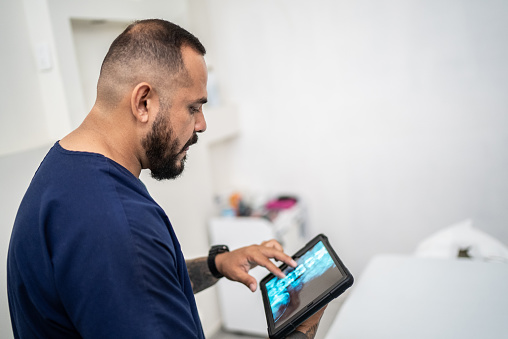 Physiotherapist using digital tablet looking for x-ray at medical clinic