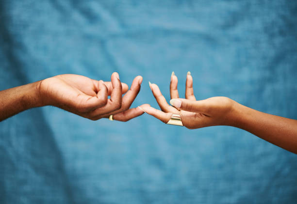 Two African hands reaching for each other isolated on studio background. Unregonisable male and female African arms with fingers gently touching