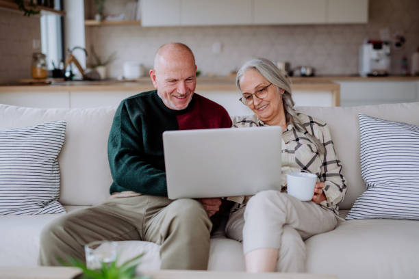 istock Cheerfull senior couple sitting home on sofa and using laptop 1401144860