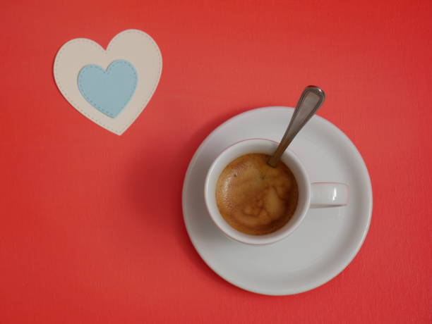 A cup of coffee and two paper hearts. Orange background. Flat lay. Father'day concept or love concept