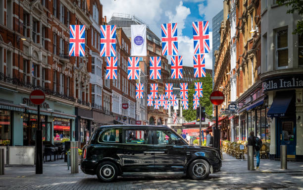 ein elektrisches schwarzes taxi in tx city wartet unter jubilee bunting im zentrum von london auf passagiere - black cab stock-fotos und bilder