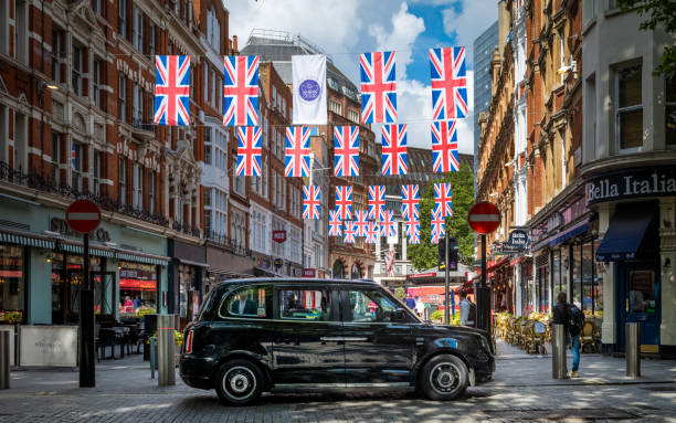 un taxi negro eléctrico de tx city espera a los pasajeros bajo el bunting jubilee en el centro de londres - black cab fotografías e imágenes de stock