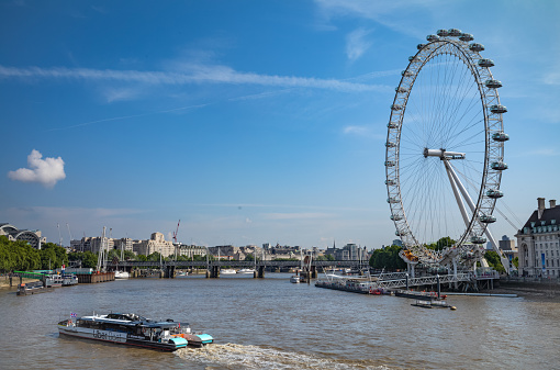A river taxi on the River Thames in London, UK, seen looking towards the London Eye as seen from Westminster Bridge.