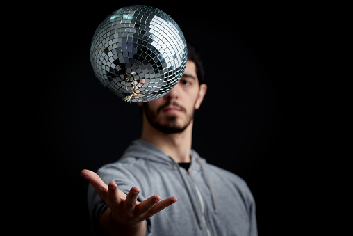 A disco ball levitating above a man's hand, old school party concept