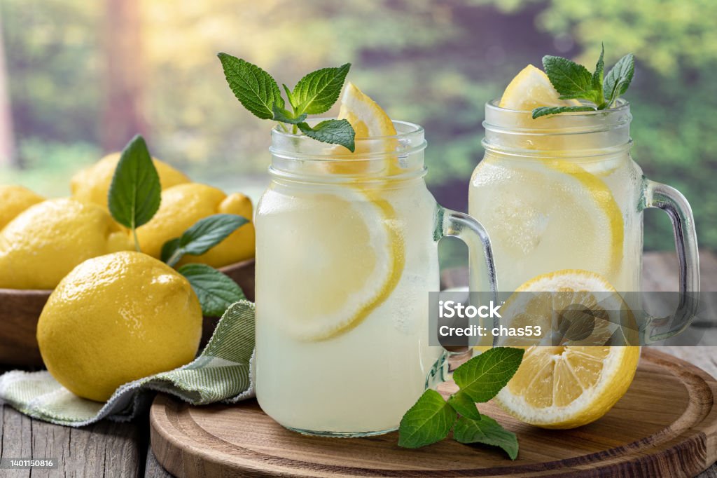 Two glasses of lemonade with mint and lemons Two glasses of lemonade with mint and lemon on a wooden tray with rural background Lemonade Stock Photo