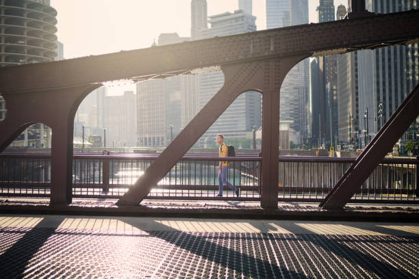 mann, der im morgenlicht auf der brücke geht - skyscraper city life urban scene building exterior stock-fotos und bilder