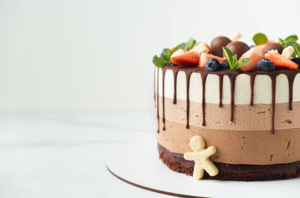 istock Brown layered cake Three chocolates decorated with bluberries, strawberries and chocolate drips on top. White background. 1401152550