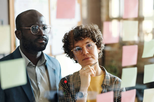 istock Employees reading sticky note on glass wall 1401153774