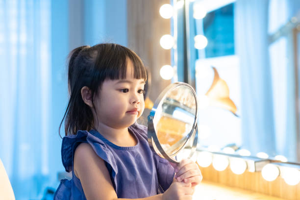 wspaniała azjatycka dziewczynka w niebieskiej sukience wyglądającej w lustrze - fashion male beauty confidence elegance zdjęcia i obrazy z banku zdjęć
