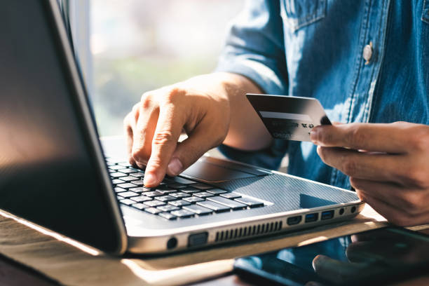 istock Businessman hand holding credit card with using laptop for online shopping while making orders at home. business, lifestyle, technology, ecommerce, digital banking and online payment concept. 1401154876