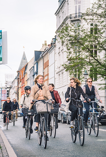 Copenhagen, Denmark - May 23 2022: Girls and cyclists riding on a bike road in Christianshavn neighborhood, Copenhagen, Denmark, vertical