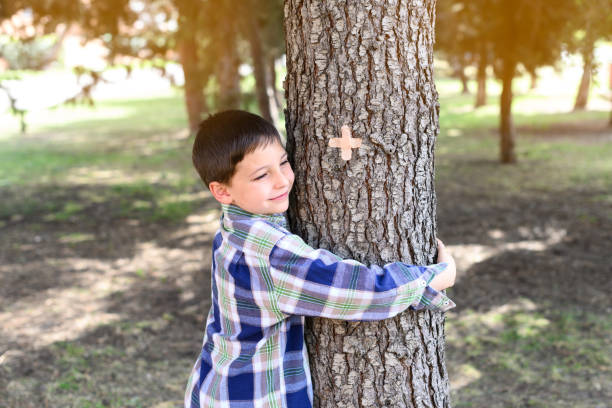 Happy child hugging a tree trunk in a forest. Concept of caring for the environment