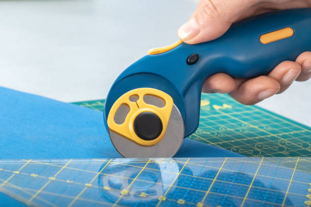 istock Tailor's knife in a woman's hand cuts the fabric according to the pattern. Close-up. 1401156891
