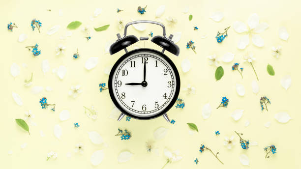 Black vintage alarm clock on yellow flowers background