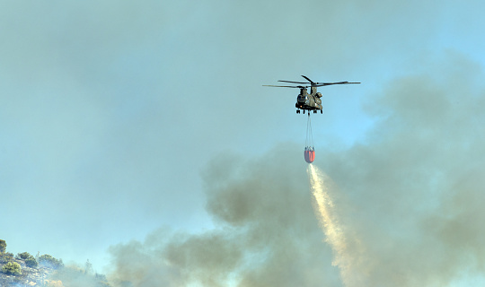 Athens, Greece, June 4, 2022: A firefighting Boeing CH-47D Chinook helicopter operates in Hymettus mount wildfire near Glyfada suburb of Athens.