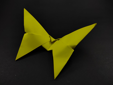 Paper craft in the shape of a yellow butterfly isolated on a black background, Not Focus