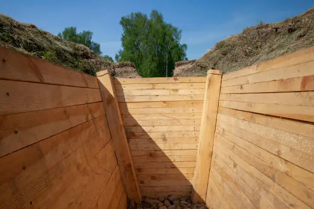 Photo of dug in the ground and reinforced with improved boards trench