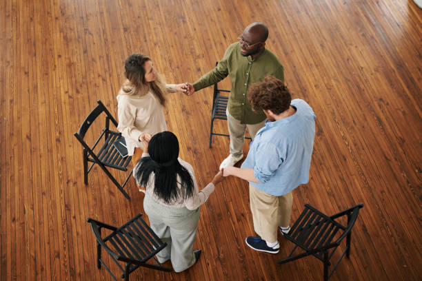 istock Above shot of four interracial people holding by hands while standing in circle 1401166651