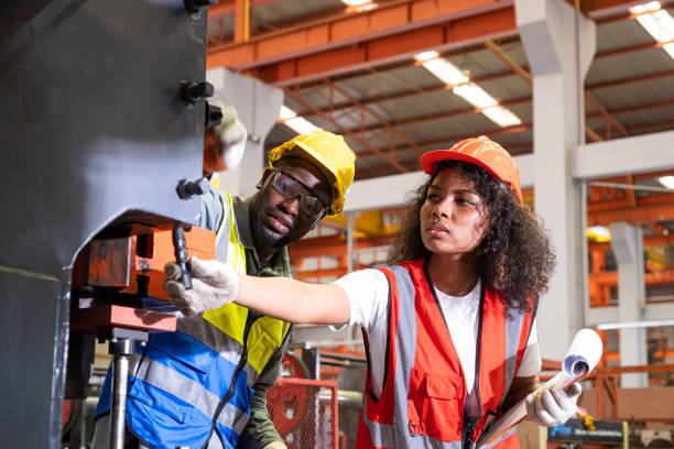 istock African mechanical engineer team, wearing safety equipment. While doing machine maintenance and safety control while work inside of factory area. With blurred background of heavy machine. 1401167132
