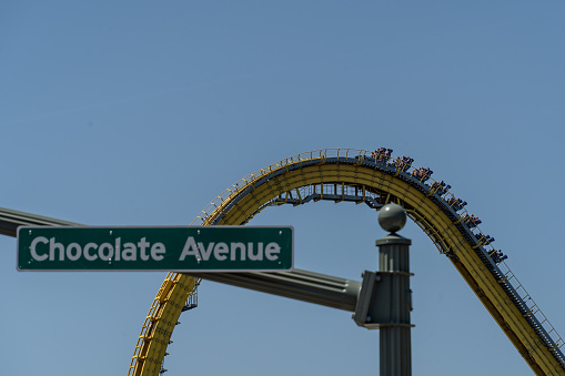 Hershey Pennsylvania, May 30, 2022: Chocolate Avenue street sign with Hersheypark roller coaster in the background.