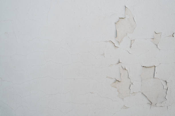 Gray paint cracked plaster on concrete wall, outdoors. Textured rough background with copy space.