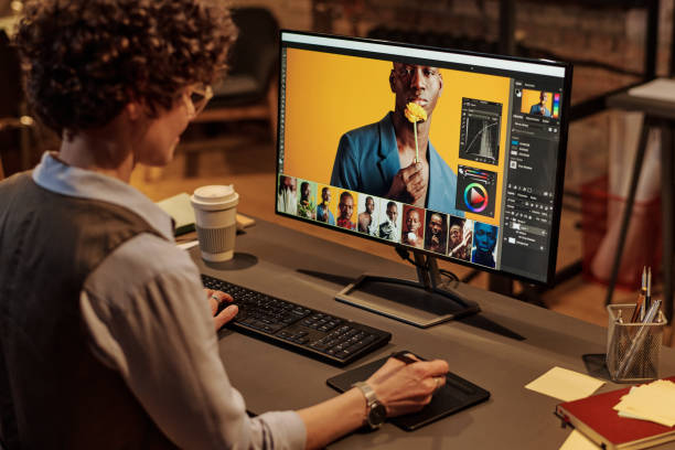 Young graphic designer working in office Rear view of woman using graphic tablet to edit photos on computer while sitting at her workplace at office graphic designer photos stock pictures, royalty-free photos & images