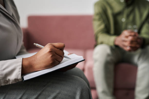 istock Hand of young female psychoanalyst making notes in notebook at session 1401169997