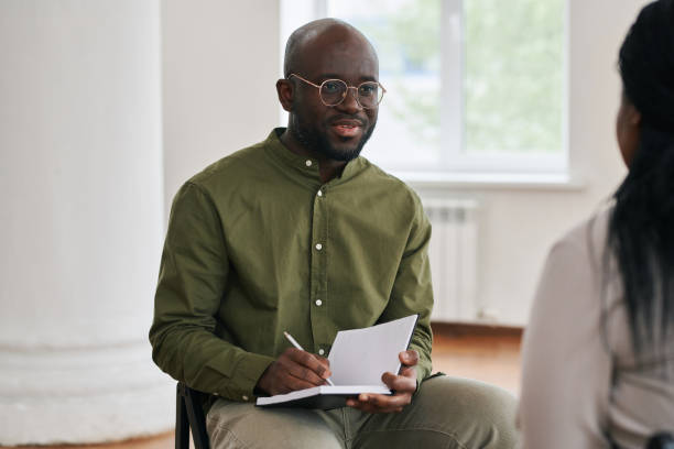 istock Young confident man making notes in notebook during talk with female patient 1401170014