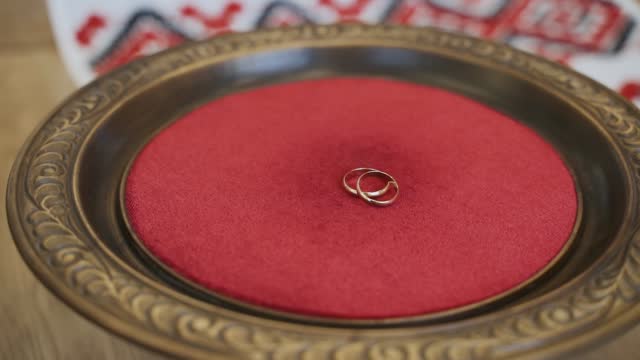 Two wedding rings lie in old wooden bowl with a red textile center