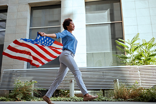 Young woman holding American flag and running