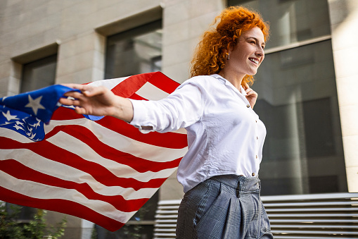 Young woman holding American flag and running