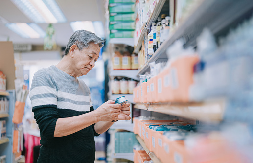 asian chinese senior man looking for medical supplies in drug store pharmacy shop