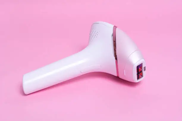 Photo of Photoepilator on a pink background. Hair removal tool.