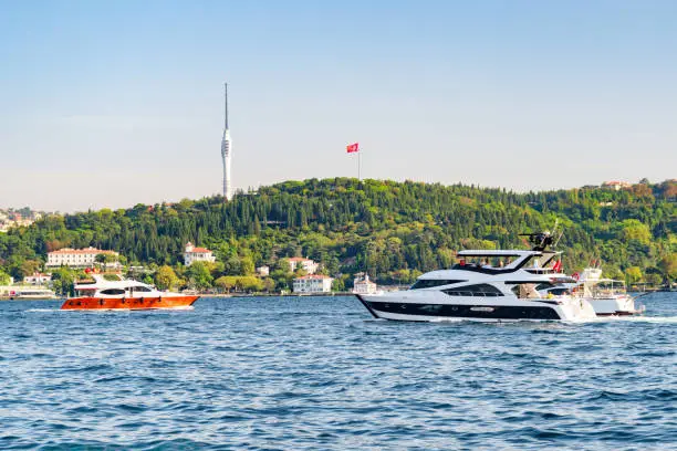 Speedboats are crossing the Bosporus in Istanbul, Turkey. The Camlica Tower is visible in background. Istanbul is a popular tourist destination in the world.