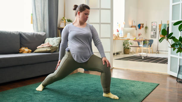 istock Young female with Down syndrome doing exercise for stretching legs 1401177168